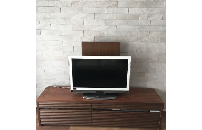 石張り調の壁面に設置された大川家具の無垢テレビボード(オーキタ家具)