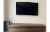 空気清浄機が横に設置された大川家具のテレビボードと壁掛けテレビ