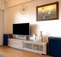 大川家具のテレビボードとスピーカー・時計・鏡が配置されたオシャレなリビング(ルームズ大正堂)