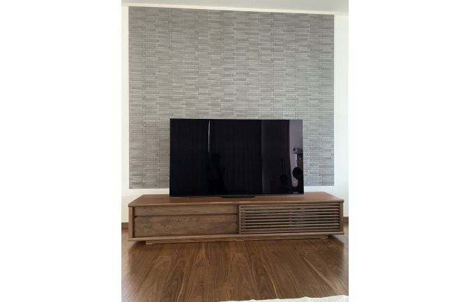 石張り調の壁面に設置されたウォールナット色の大川家具のテレビボード