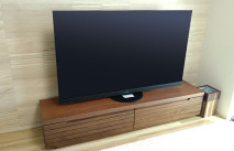 石目調の壁面に設置された大川家具のテレビボード(ルームズ大正堂本店)