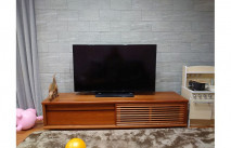 石目調の壁面に設置された大川家具のテレビボード