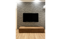 石張り調の壁面に設置された岸和田市K.H様の無垢テレビボード(オーキタ家具)
