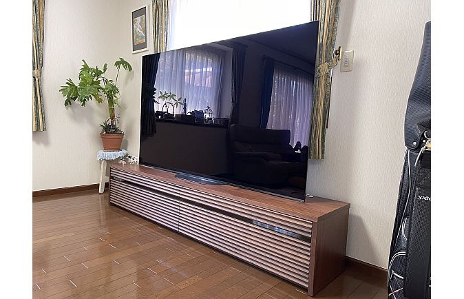 大型のテレビが設置された大川家具のテレビボードと観葉植物