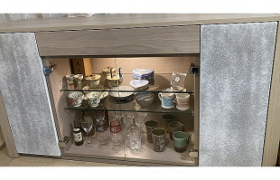 陶器やグラスがLEDライトで照らされた大川家具のキュリオケース(近新)