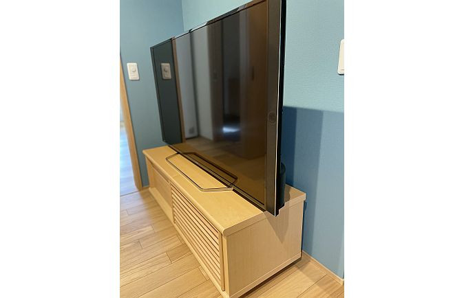 ブルーの壁に設置された大川家具のテレビボード