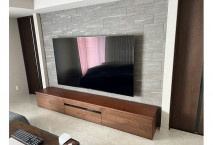 石張り調の壁面に設置された壁掛けテレビと大分市Y.M様のテレビボード